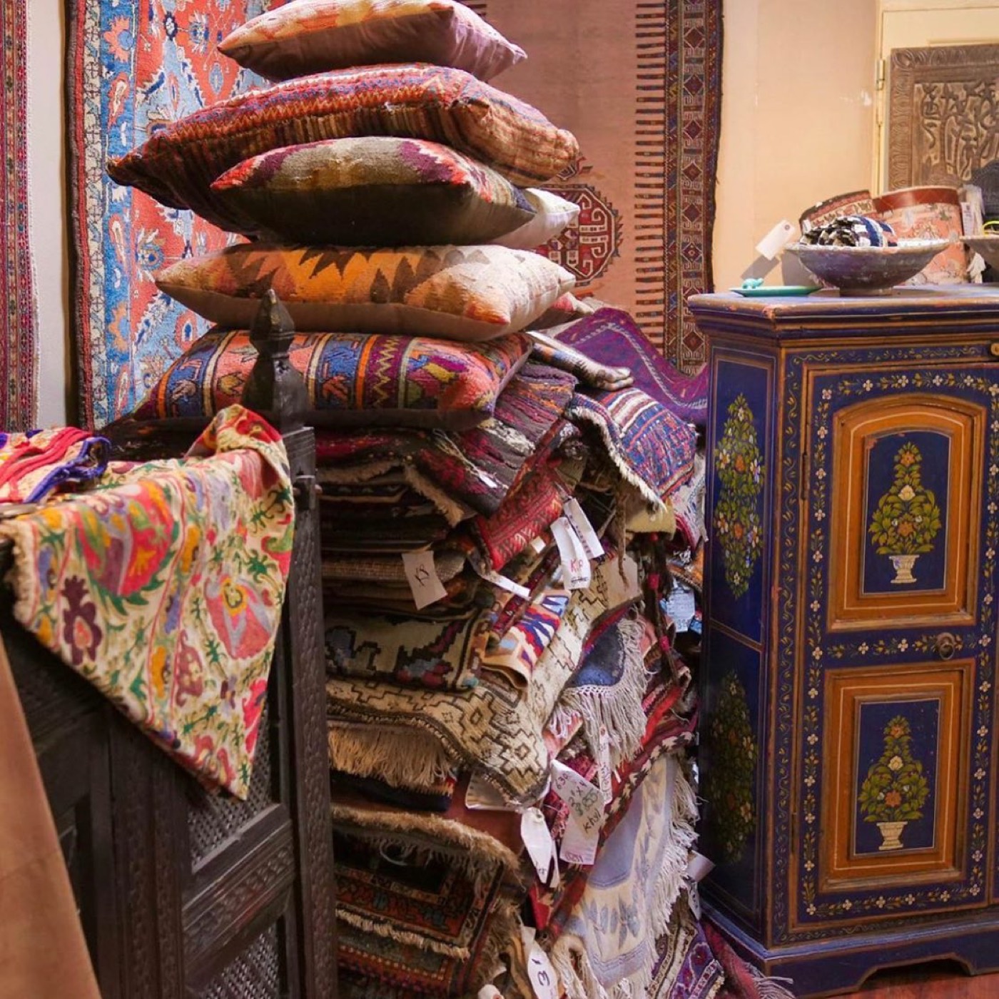 Kilims, cushions and painted chests stacked inside Khyber Pass Gallery
